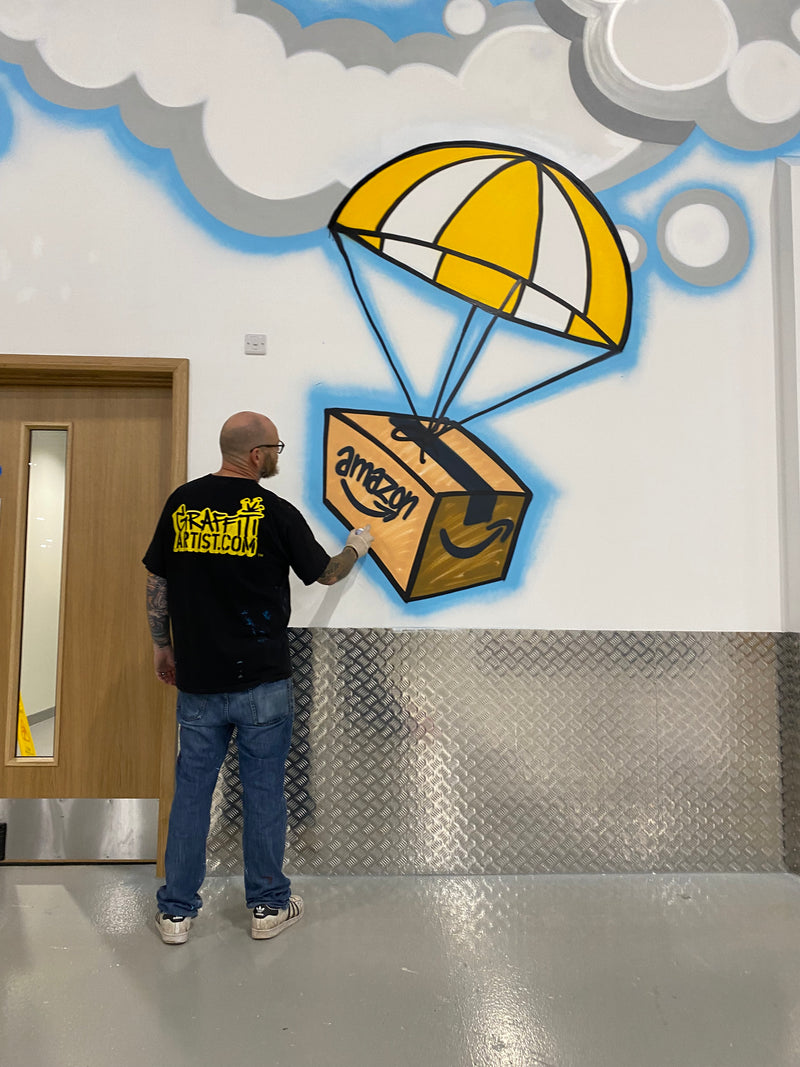 Person wearing a black cap with yellow text in front of a colorful mural on a wall.
