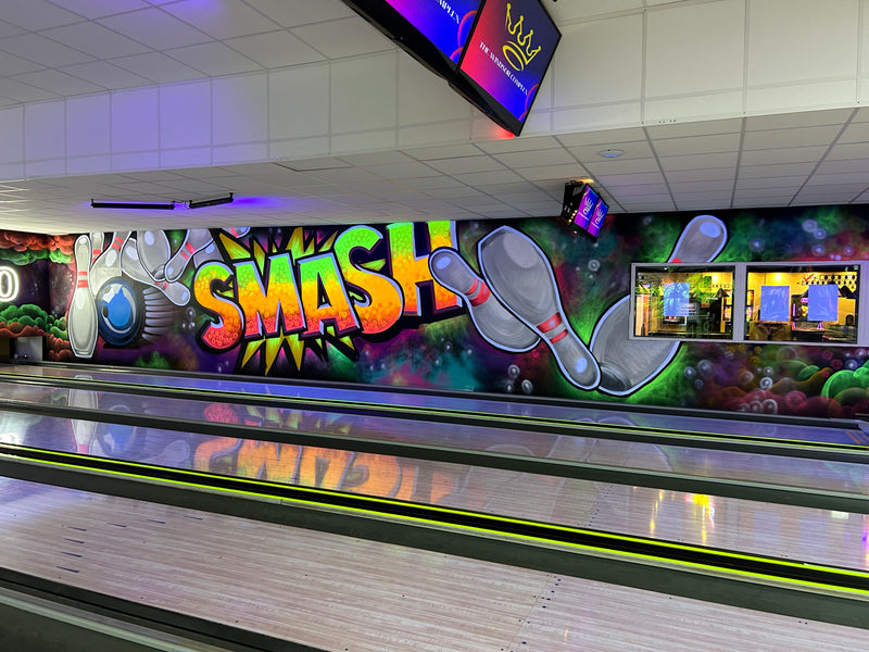 Bowling alley with colorful 'SMASH' mural and digital screens on the wall.