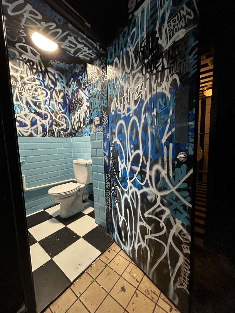 Graffiti-covered wall with a checkered floor and light fixture.