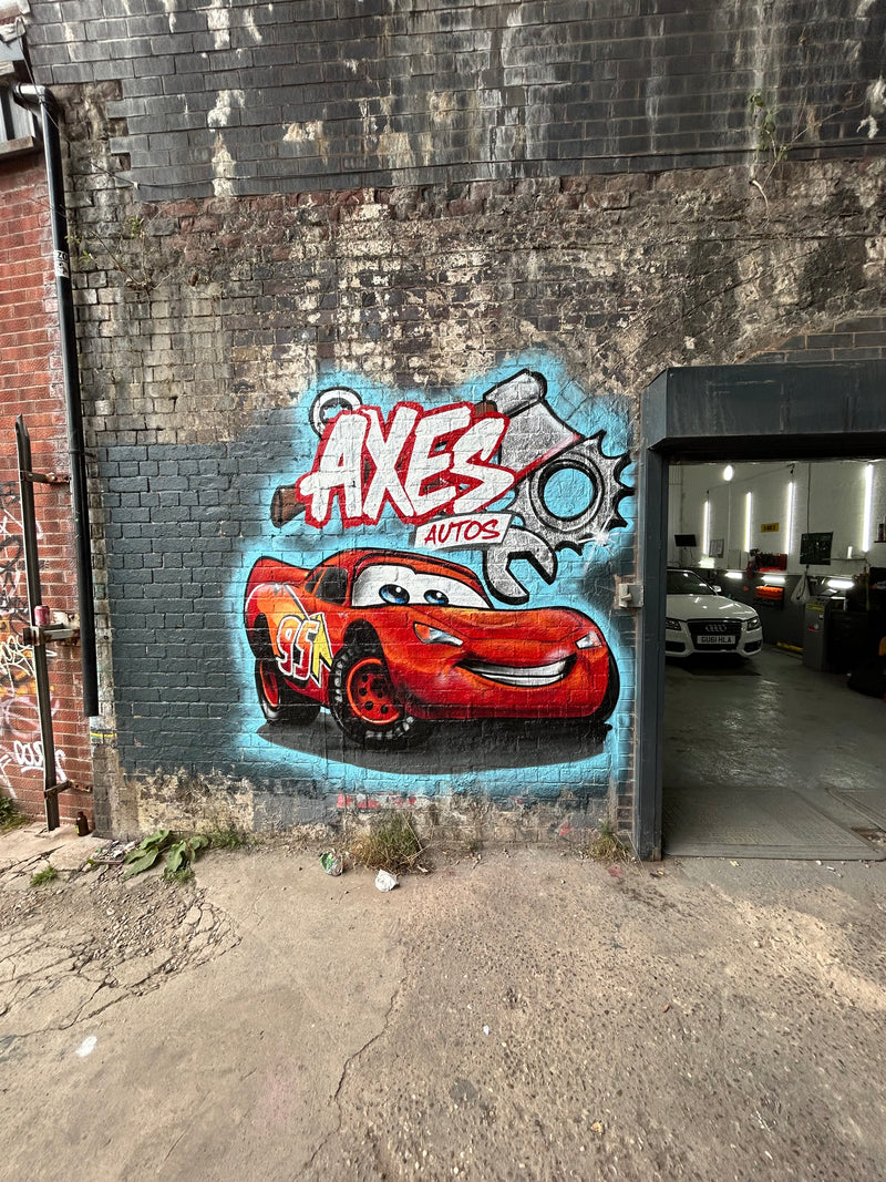 Graffiti of a red car with 'AXES' branding on a textured wall.