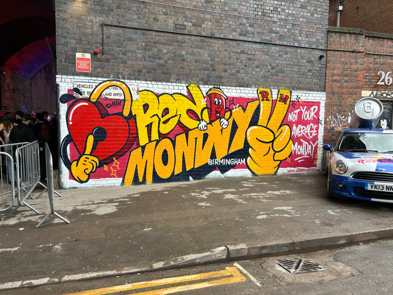 Graffiti on a brick wall with a car parked below.