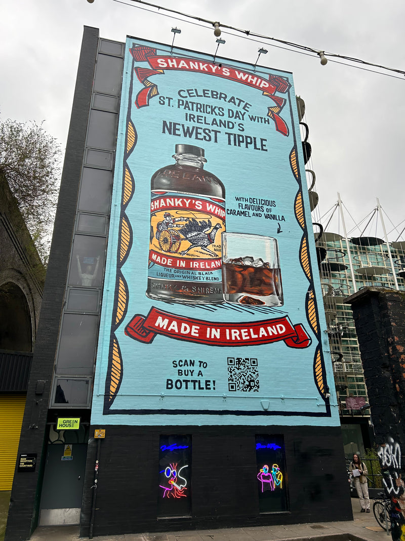 Shankly's Whip advertisement on a building facade with a QR code and bottle illustration.