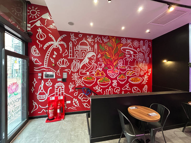 Restaurant interior with a red wall featuring artistic white line drawings and a wooden table.