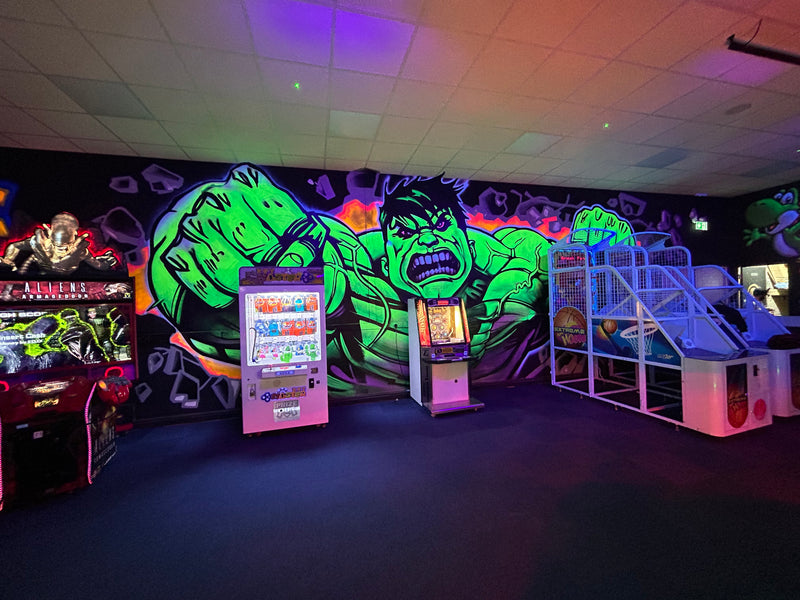 Arcade room with colorful wall art featuring a green superhero character.