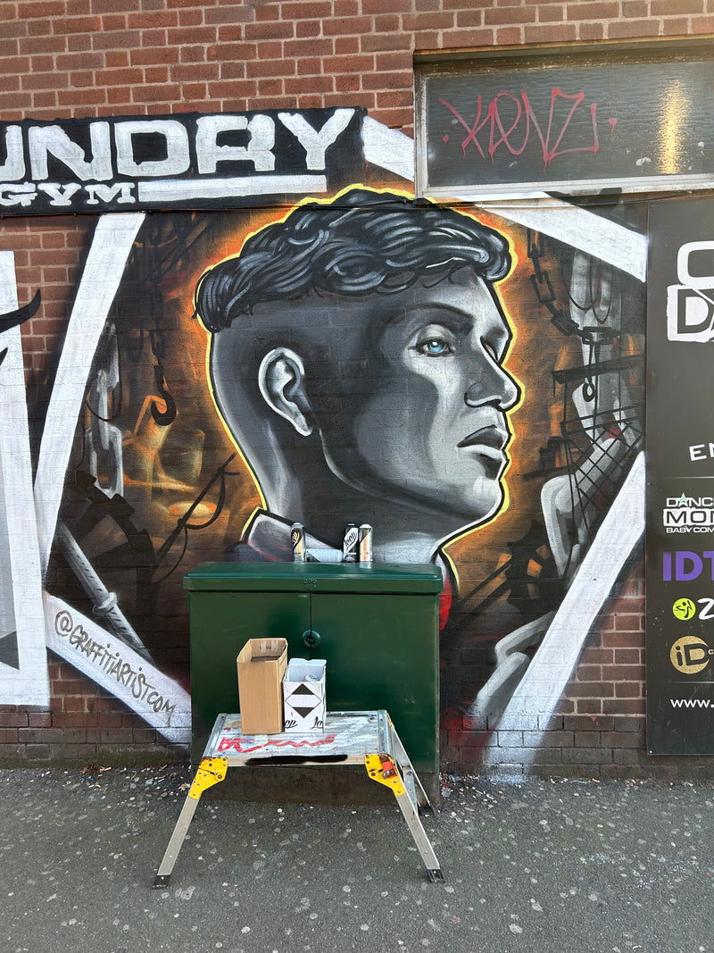 Street art of a face on a wall with various brand logos and text.